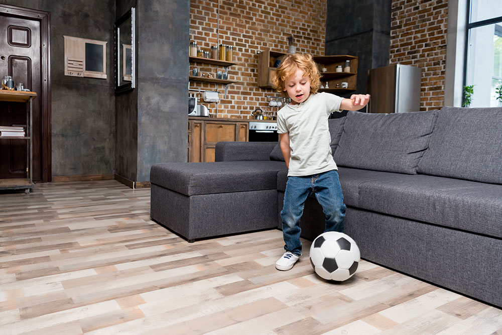 entzückender kleiner Junge, der zu Hause mit Fußball spielt